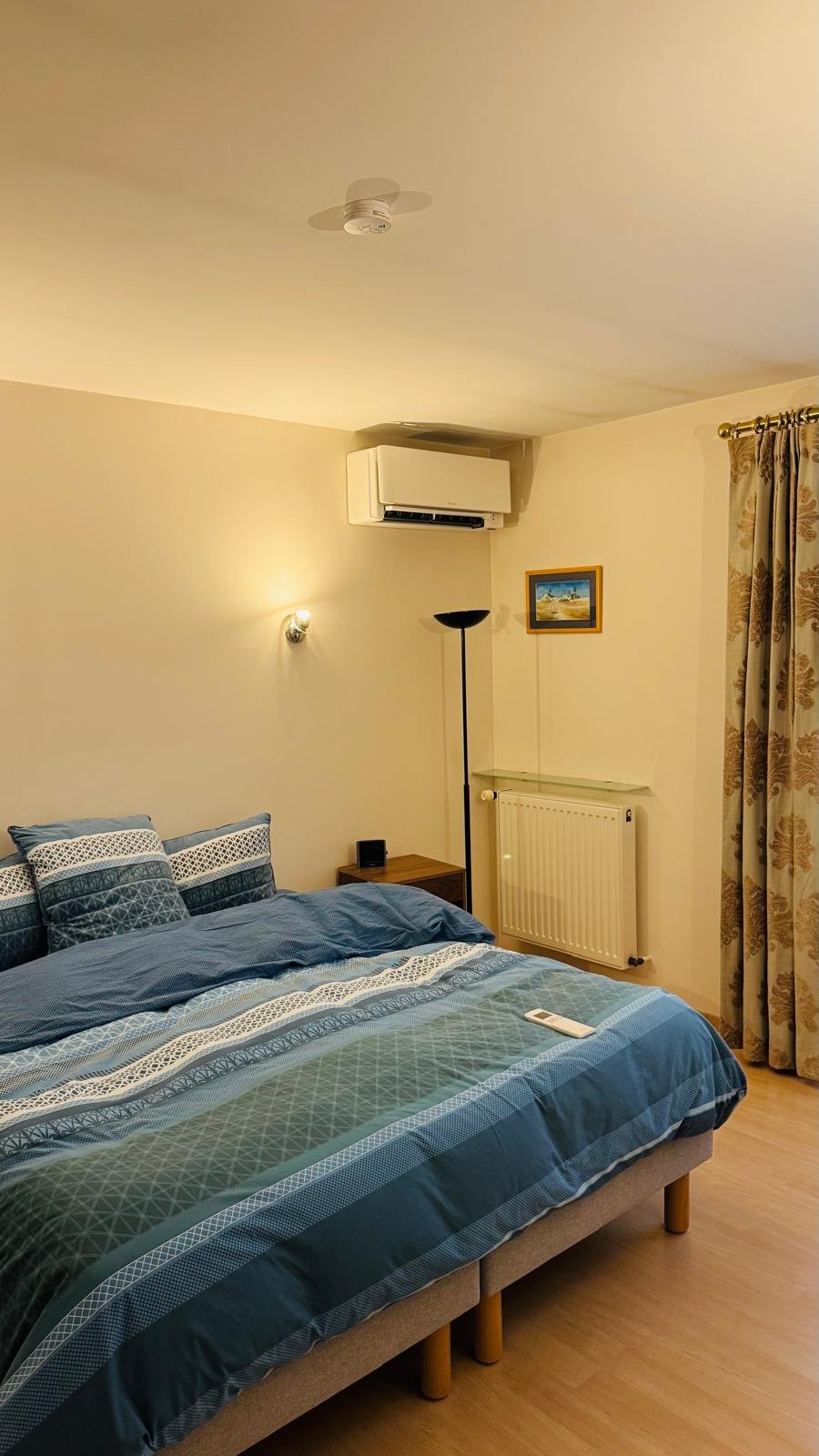 Split mural installé dans une chambre résidentielle au-dessus d'un lit double