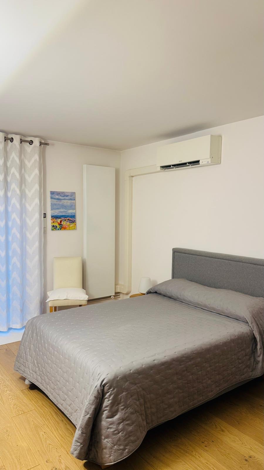 Split mural dans une chambre résidentielle moderne avec lit gris