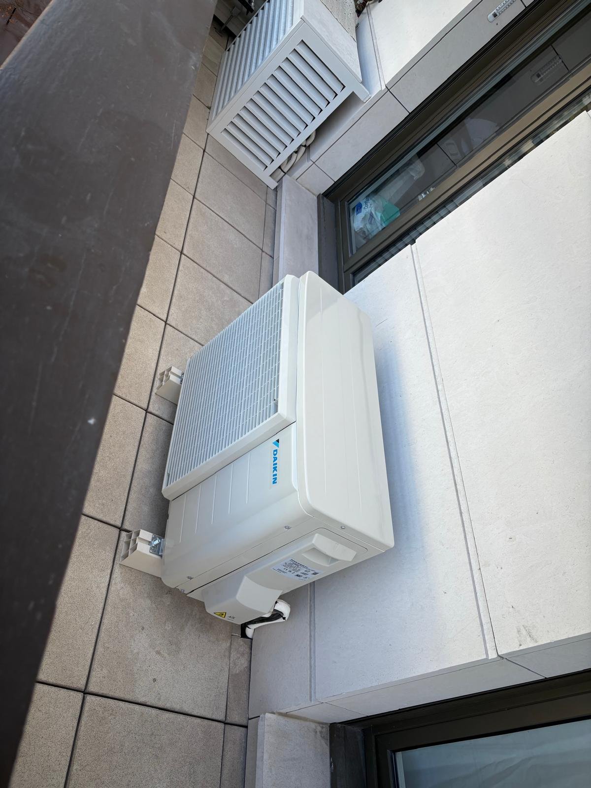 Unité extérieure Daikin fixée en console murale sur une terrasse carrelée