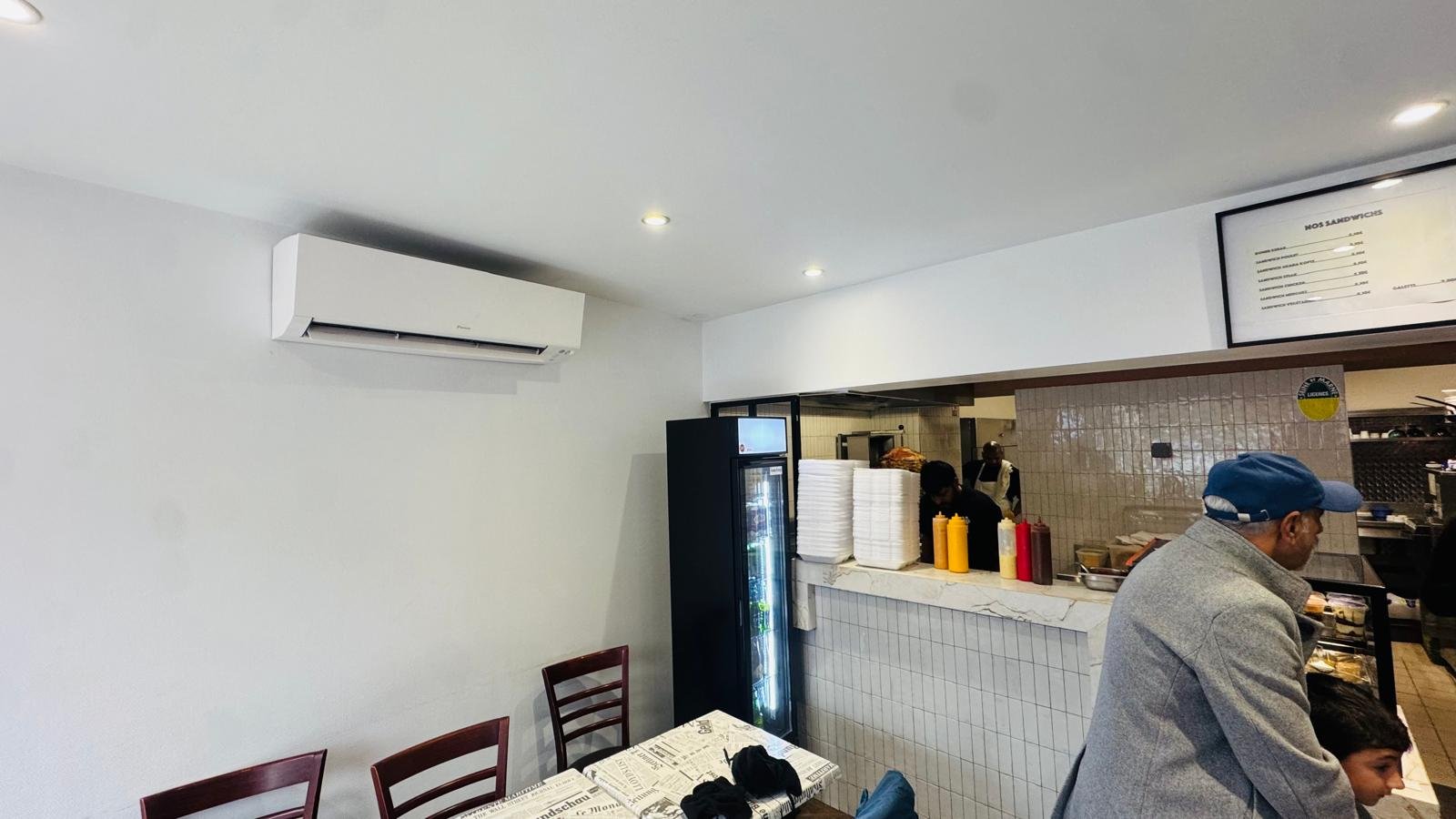 Split mural Daikin installé dans un restaurant sandwicherie, vue depuis le comptoir