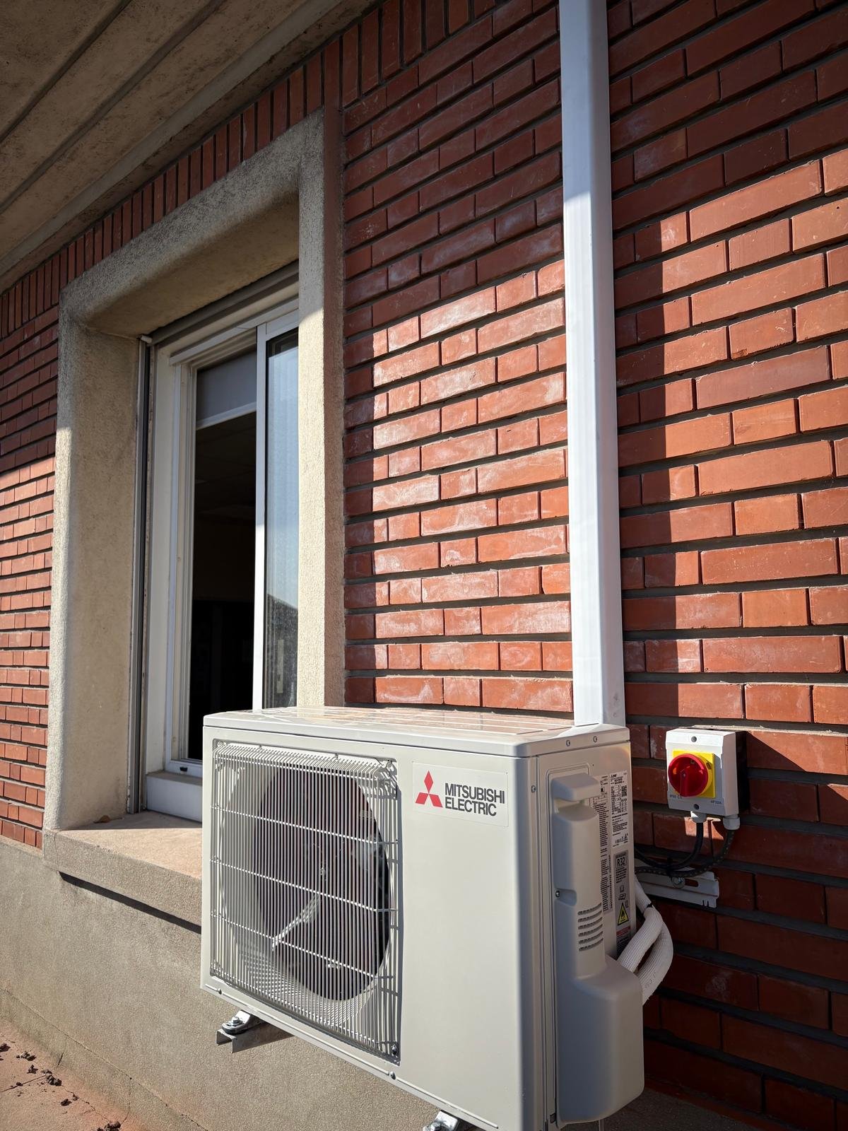Vue d'ensemble d'une unité extérieure Mitsubishi Electric installée sur un bâtiment en brique